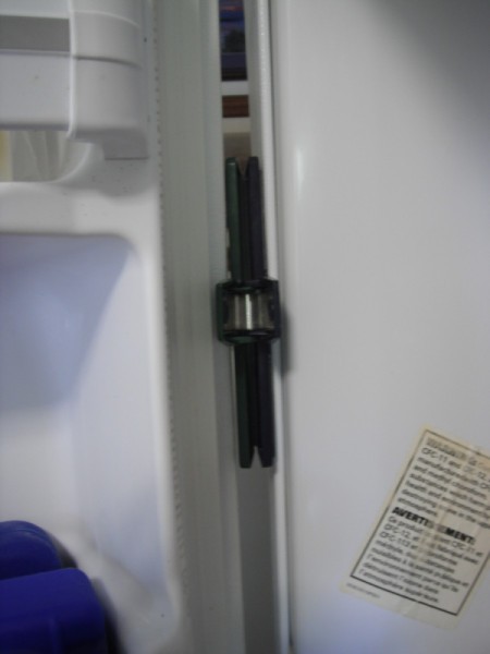 A freezer that has a chip clip placed to wedge the door open.