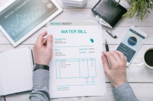 Man holds invoice of water usage over desk.