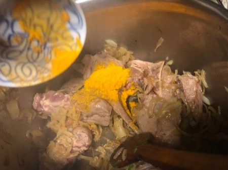 adding turmeric to lamb and onions in pan