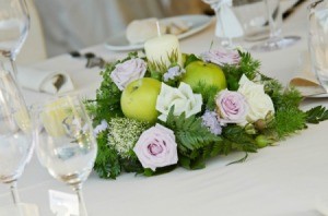 Candle centerpiece with apples roses and sprigs of fir.