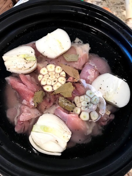 Chicken, garlic , onion, bay leaves and broth in slow cooker