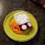 A plate of ranch dip with vegetables.