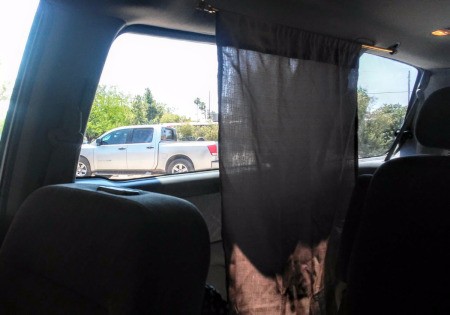 A curtain in a minivan next to a carseat.