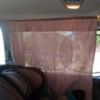 A curtain in a minivan next to a carseat.