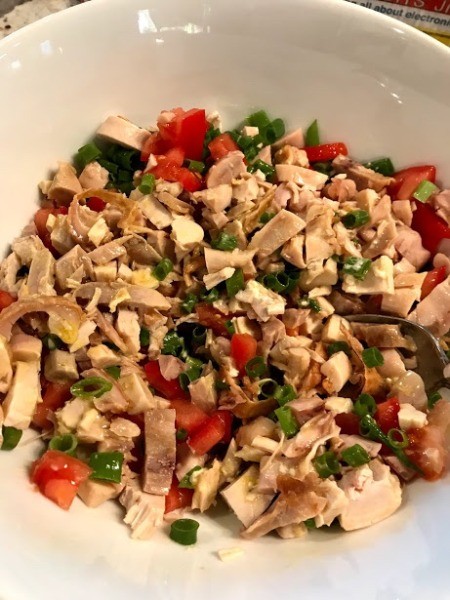 tossing chicken , tomatoes and green onions