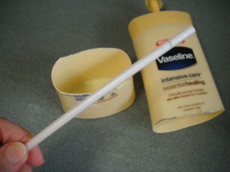 A bottle of lotion with the bottom and tube removed