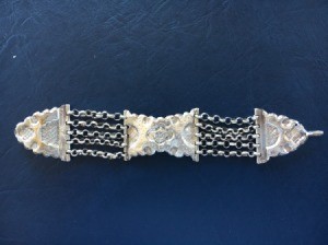 An old silver bracelet with a floral pattern.