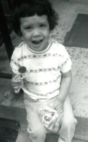 A black and white photo of a child holding a lollipop.