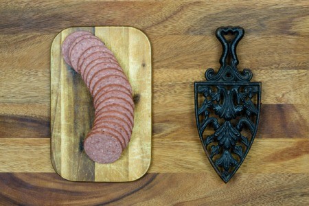 Sliced summer sausage on a cutting board.