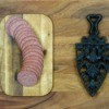 Sliced summer sausage on a cutting board.