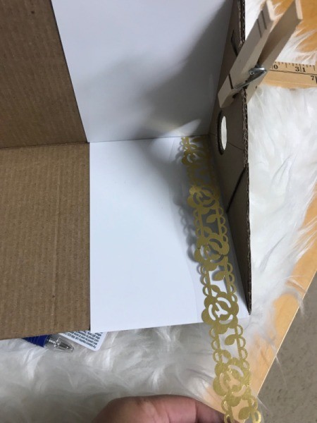 Recycled Cardboard Shelf - clothespin holding end while decorating with tape at the edges