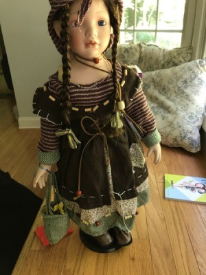 Identifying a Porcelain Doll - doll wearing a brown dress with striped shirt underneath