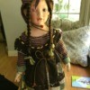 Identifying a Porcelain Doll - doll wearing a brown dress with striped shirt underneath
