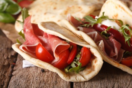 Italian piadina flatbread stuffed with ham and vegetables close-up