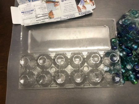 A plastic egg carton next to glass gems.