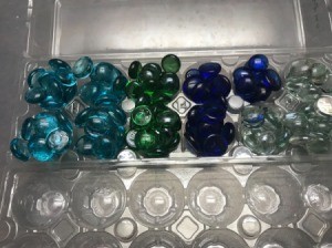 Glass gems organized inside a clear plastic egg carton.