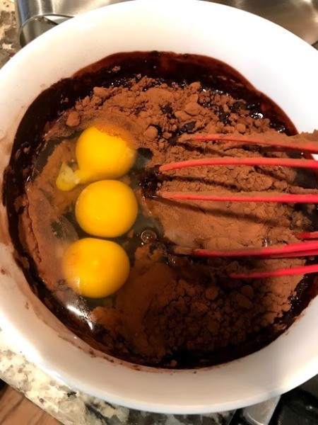 adding eggs and cocoa to chocolate