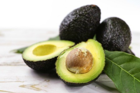 Halved avocado with leaves and whole avocados