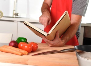 Unrecognizable man at kitchen following recipe book.