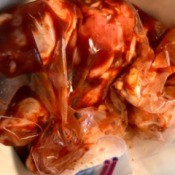 Chicken in a plastic bag with BBQ sauce being marinated.