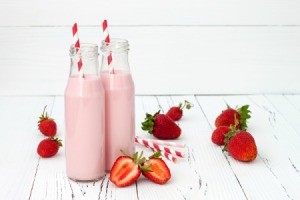 Strawberry milk in glass bottles with paper straws.