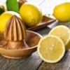 Wooden lemon juicer surrounded by lemons.