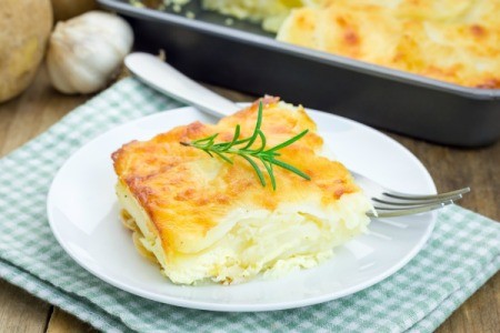 Slice of White Cheddar Au Gratin Potatoes on a white plate.
