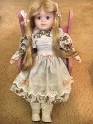 Identifying a Porcelain Doll  - doll with long blond hair sitting on a pink chair