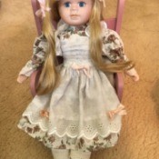 Identifying a Porcelain Doll - doll with long blond hair sitting on a pink chair