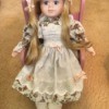 Identifying a Porcelain Doll  - doll with long blond hair sitting on a pink chair