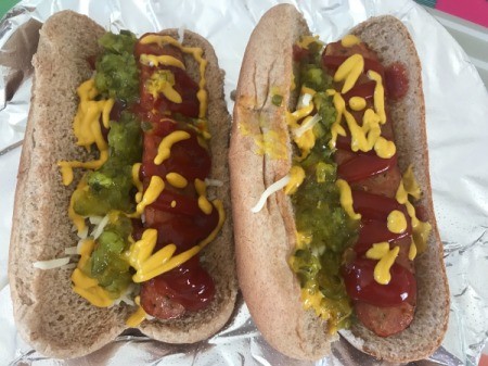 Half hot dogs on buns with condiments.