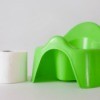 Green plastic potty chair, with a roll of toilet paper.