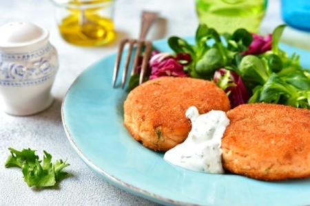 Salmon Patties on a blue plate with greens.
