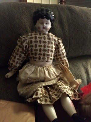 Identifying an Antique Porcelain Doll  - doll with molded hair wearing a tan and brown print dress and tan apron
