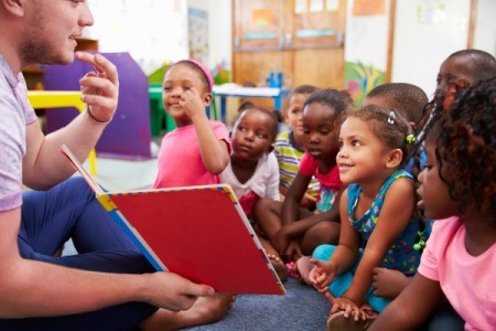 Volunteer teacher reading to a class of kids