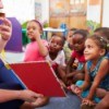 Volunteer teacher reading to a class of kids