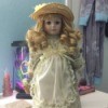 Identifying a Porcelain Doll - doll wearing a straw hat and a print dress with a lace edged apron