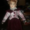 Identifying a Porcelain Doll - doll wearing a dark red dress with a floral jacket