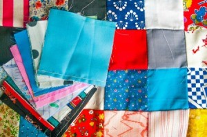 Patchwork quilt with a pile of quilting squares on top.