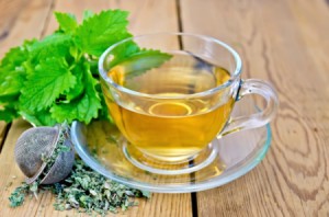 cup of lemon balm tea with fresh and dried leaves