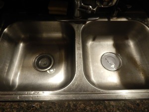 A sink with plugs in the drain and a small amount of standing water.