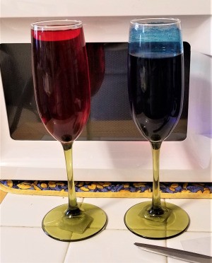 A pair of champagne flutes partly full of colored water.