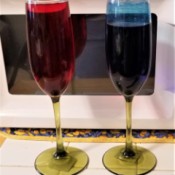 A pair of champagne flutes partly full of colored water.