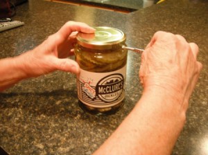 A paint key being used to open a jar of pickles.