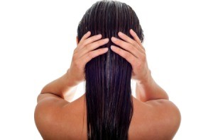 Back of woman's head holding her wet hair.