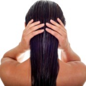 Back of woman's head holding her wet hair.