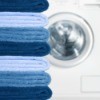 Pile of blue towels in different shades near a dryer.