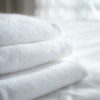 Folded white towels on a white sheet.