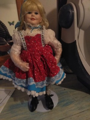 Identification and Value of a Porcelain Doll - doll wearing a red print pinafore dress