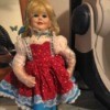 Identification and Value of a Porcelain Doll - doll wearing a red print pinafore dress